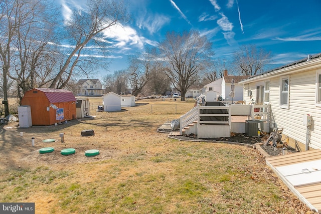 view of yard with an outbuilding, fence, a shed, cooling unit, and a residential view