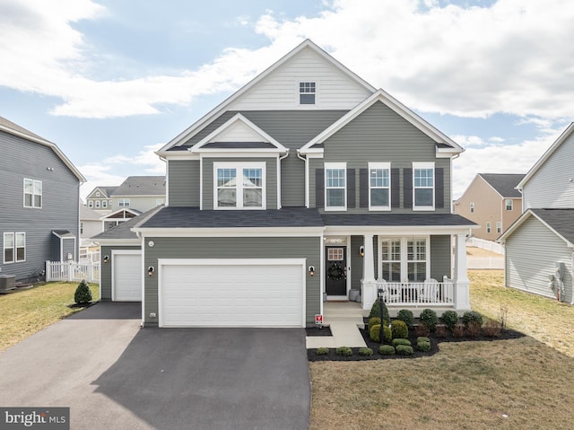 traditional home with driveway, a garage, covered porch, central AC, and a front yard