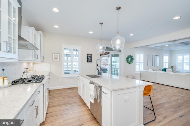 kitchen featuring light wood-style flooring, decorative backsplash, stainless steel dishwasher, white cabinetry, and a sink