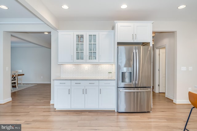 kitchen featuring light wood-type flooring, stainless steel fridge, white cabinetry, and tasteful backsplash