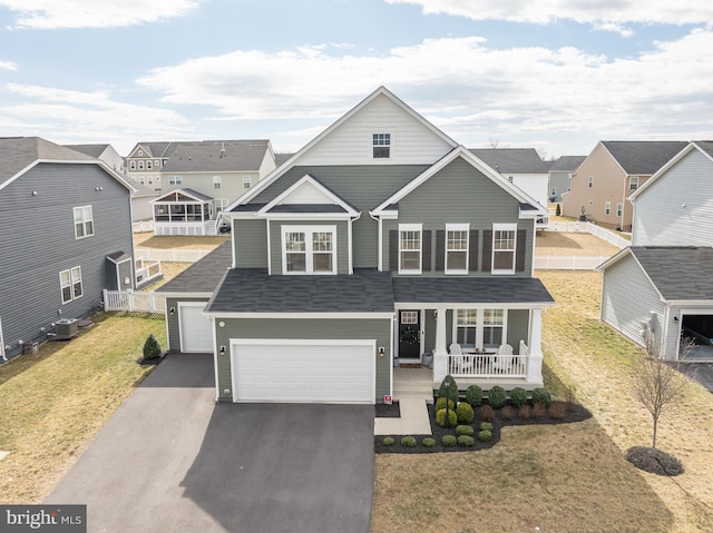 traditional home with a garage, a porch, fence, cooling unit, and a front lawn