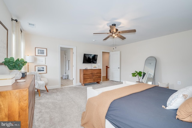 bedroom featuring light carpet, baseboards, visible vents, ceiling fan, and ensuite bathroom