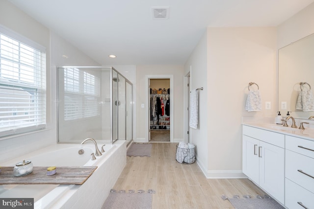 bathroom featuring wood finished floors, vanity, visible vents, a shower stall, and a walk in closet