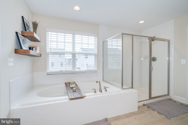 bathroom with a stall shower, a garden tub, recessed lighting, and wood finished floors