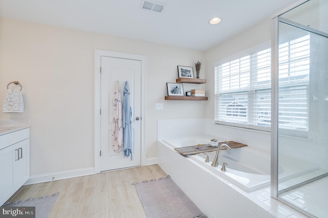 bathroom featuring a garden tub, recessed lighting, visible vents, wood finished floors, and baseboards