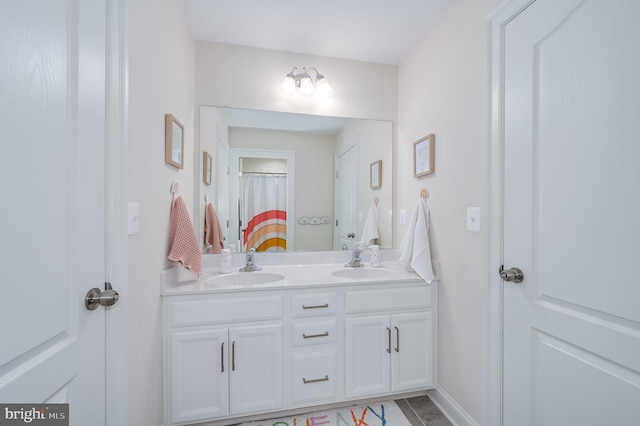 full bathroom featuring double vanity, a sink, and baseboards