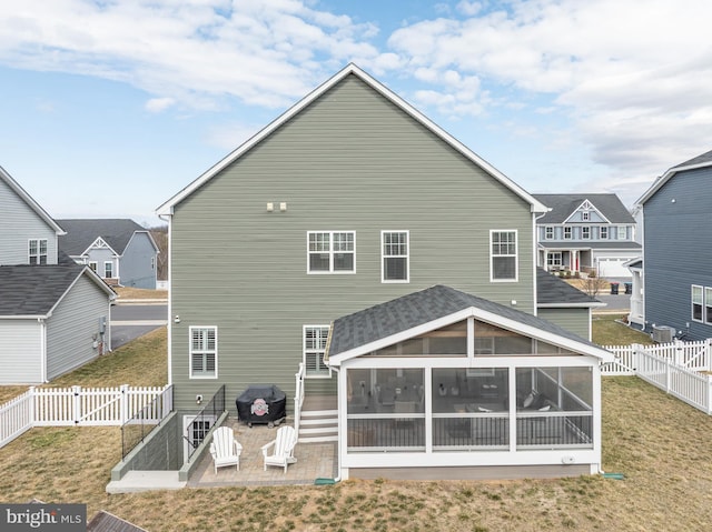 back of house featuring a sunroom, a fenced backyard, a gate, and a lawn