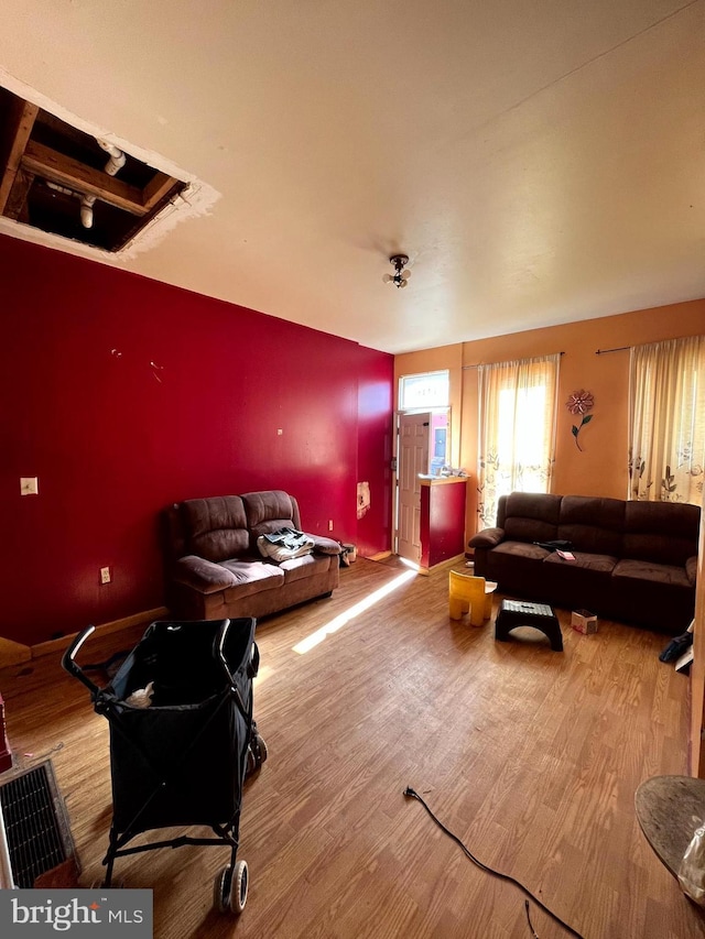 living area with an accent wall, baseboards, and wood finished floors