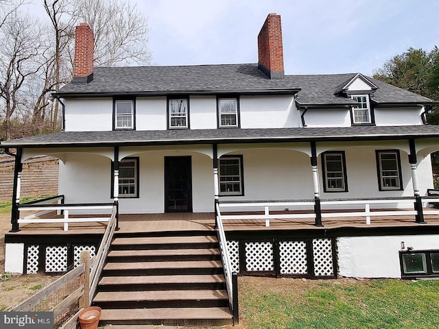 back of property featuring covered porch, a chimney, and stucco siding