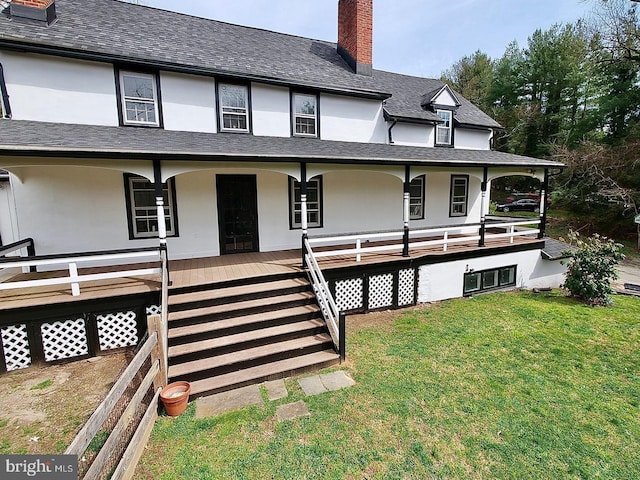 view of front of house with covered porch, roof with shingles, stucco siding, a front lawn, and a chimney