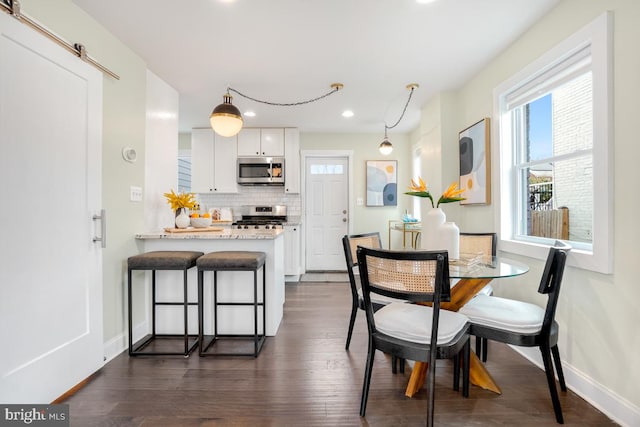 dining space featuring dark wood-style floors, baseboards, and a barn door