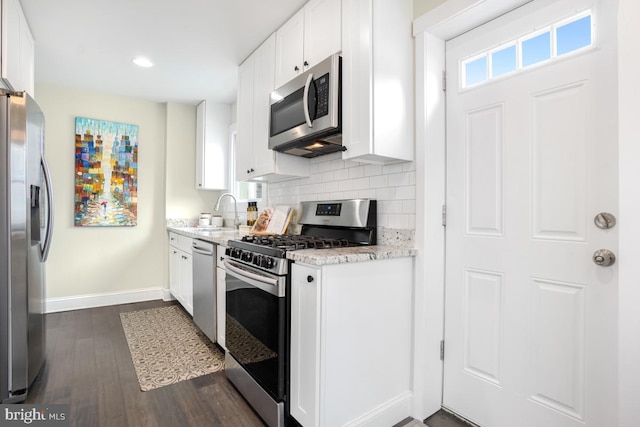 kitchen featuring stainless steel appliances, a sink, white cabinets, dark wood-style floors, and tasteful backsplash