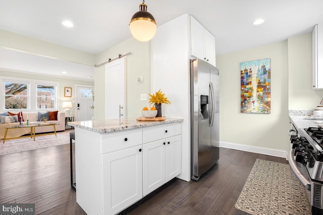 kitchen featuring a barn door, white cabinets, appliances with stainless steel finishes, light stone countertops, and dark wood-style floors