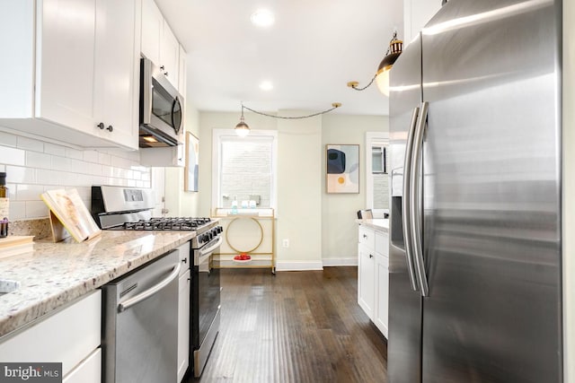 kitchen featuring light stone counters, stainless steel appliances, dark wood-type flooring, white cabinetry, and decorative backsplash