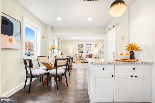 kitchen featuring light stone countertops, a barn door, white cabinets, and dark wood-style flooring