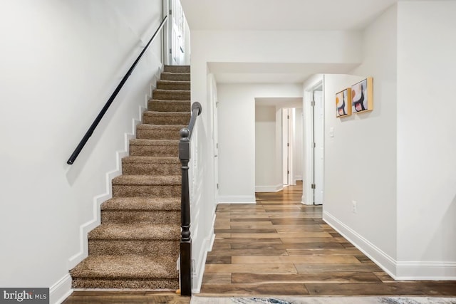 staircase with wood finished floors and baseboards