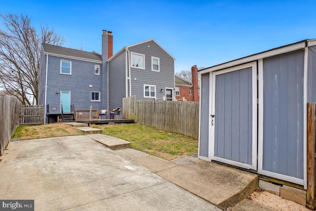 rear view of property with an outbuilding, a yard, a patio, a storage unit, and a fenced backyard