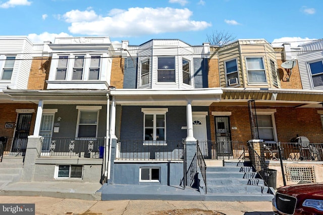 multi unit property featuring covered porch and brick siding