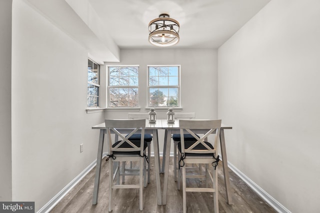 dining area featuring baseboards, an inviting chandelier, and wood finished floors