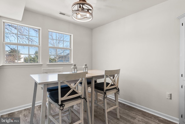 dining space featuring visible vents, baseboards, wood finished floors, and a chandelier