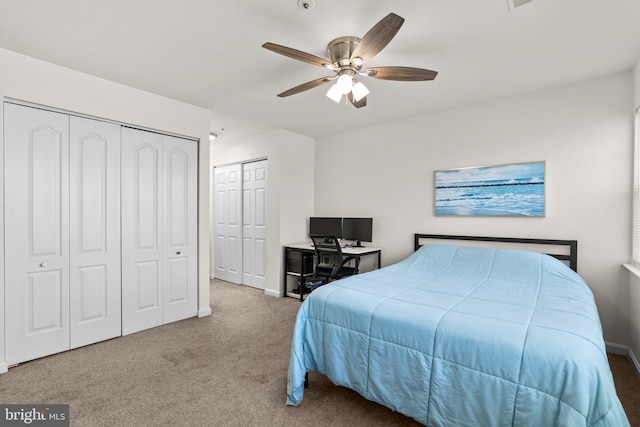 bedroom with baseboards, two closets, carpet, and a ceiling fan