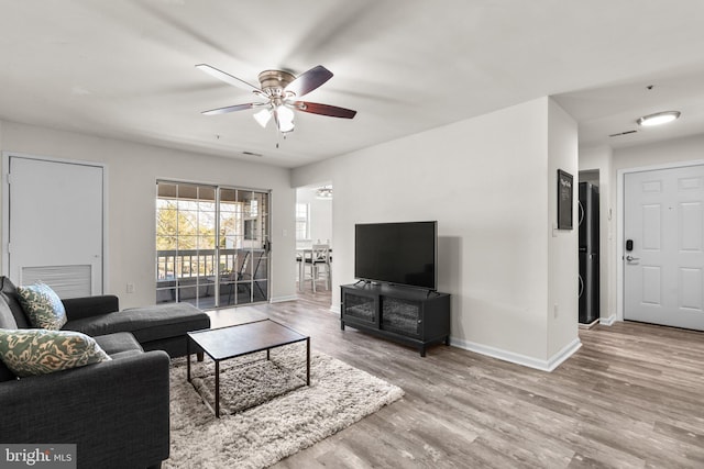 living room featuring ceiling fan, baseboards, and wood finished floors