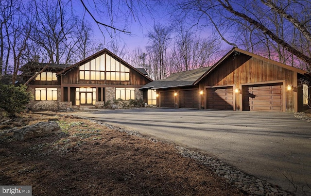 view of front of property with a garage, stone siding, and aphalt driveway