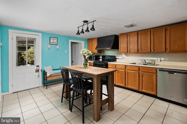 kitchen featuring a sink, light countertops, appliances with stainless steel finishes, wall chimney range hood, and brown cabinets