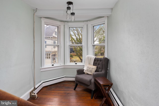 sitting room featuring a baseboard heating unit, hardwood / wood-style flooring, and baseboards