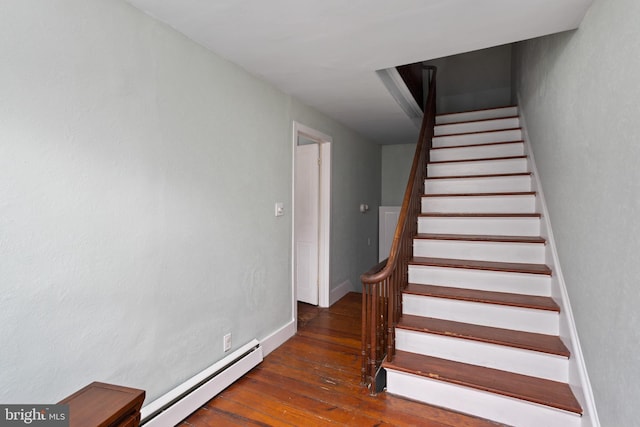 stairs featuring a baseboard heating unit, baseboards, and hardwood / wood-style floors