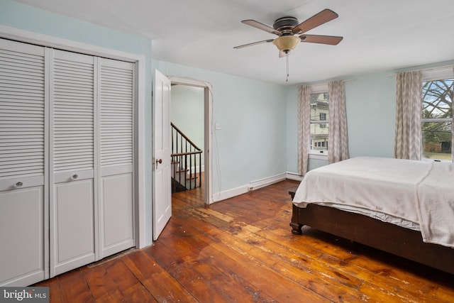 bedroom featuring a baseboard heating unit, baseboards, hardwood / wood-style floors, baseboard heating, and a closet