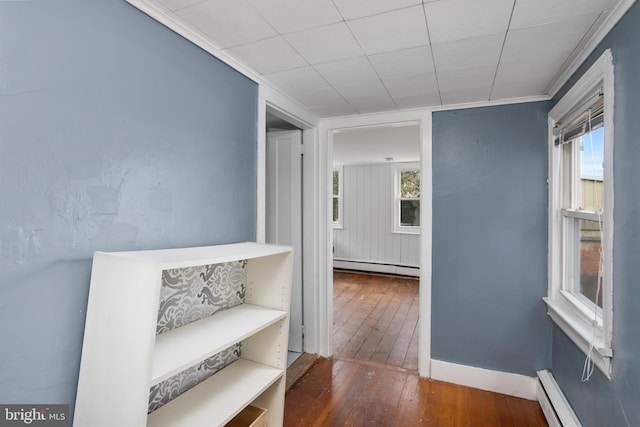 corridor featuring crown molding, a baseboard heating unit, baseboards, baseboard heating, and wood-type flooring