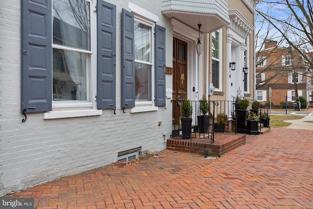 entrance to property featuring crawl space and brick siding