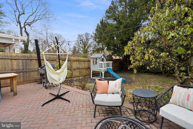 view of patio with a playground and a fenced backyard