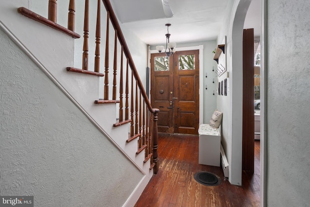 entryway with arched walkways, hardwood / wood-style floors, and stairs