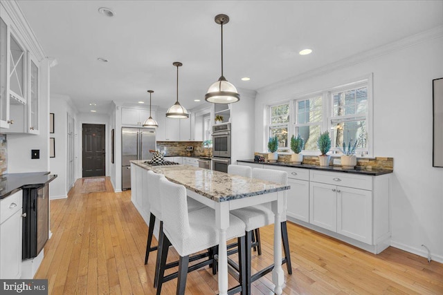 kitchen featuring stainless steel appliances, backsplash, white cabinets, and crown molding