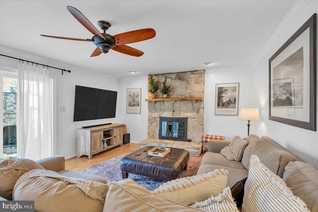 living room featuring a fireplace, light wood-style floors, ornamental molding, ceiling fan, and baseboards