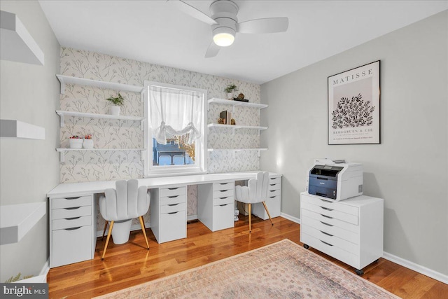 office space featuring wallpapered walls, wood finished floors, a ceiling fan, and baseboards