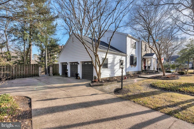 view of property exterior featuring a garage, driveway, fence, and a gate