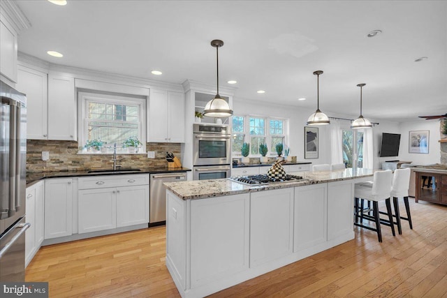 kitchen with tasteful backsplash, light wood-style flooring, stainless steel appliances, white cabinetry, and a sink