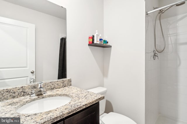 bathroom with toilet, a stall shower, and vanity