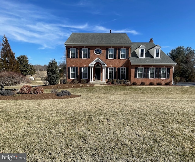 view of front of house featuring a chimney, roof with shingles, crawl space, a front lawn, and brick siding