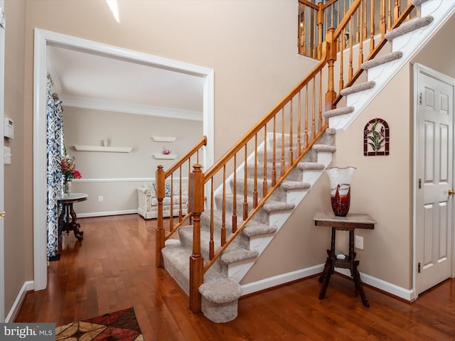 staircase featuring hardwood / wood-style flooring, baseboards, and crown molding