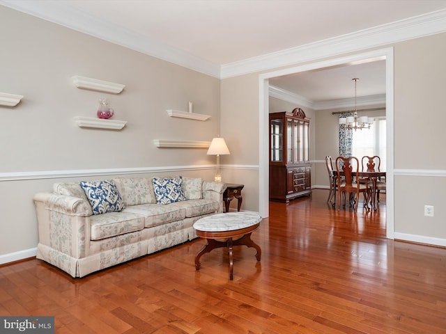 living room with baseboards, ornamental molding, hardwood / wood-style flooring, and an inviting chandelier