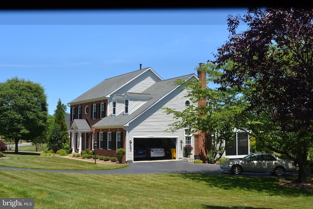 view of front of house featuring a garage, aphalt driveway, and a front yard