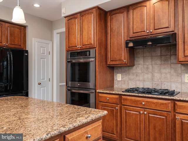 kitchen with tasteful backsplash, brown cabinets, under cabinet range hood, and black appliances