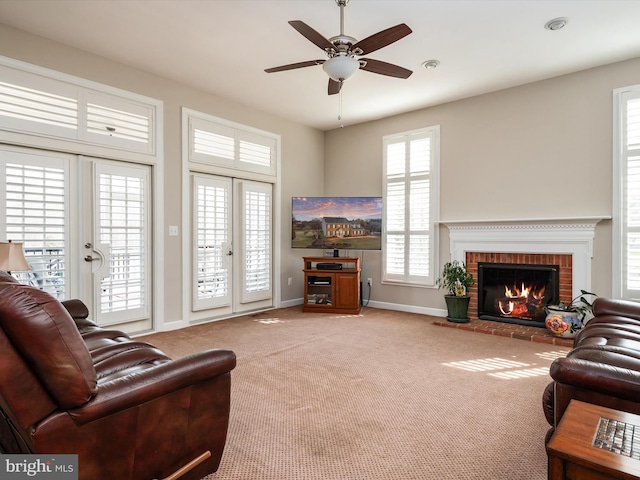 living room featuring french doors, a brick fireplace, carpet flooring, ceiling fan, and baseboards