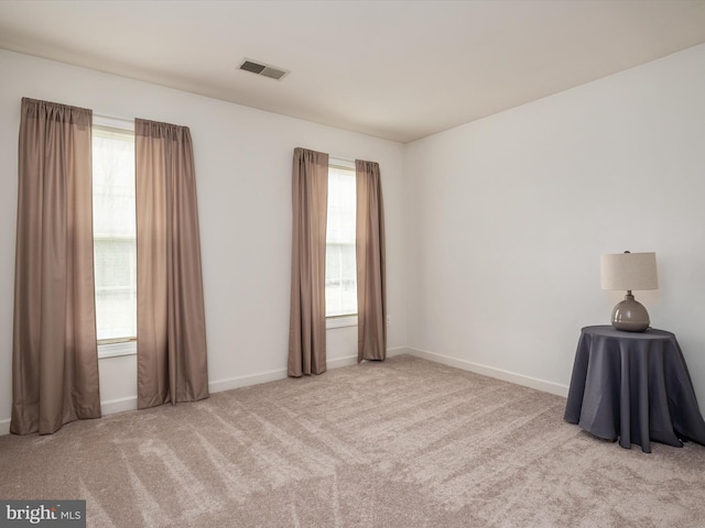 carpeted spare room with visible vents, a wealth of natural light, and baseboards