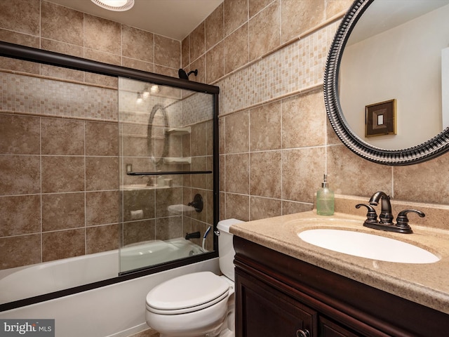 bathroom with toilet, shower / bath combination with glass door, tile walls, and vanity