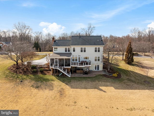 back of house featuring a patio, a chimney, a sunroom, a wooden deck, and stairs